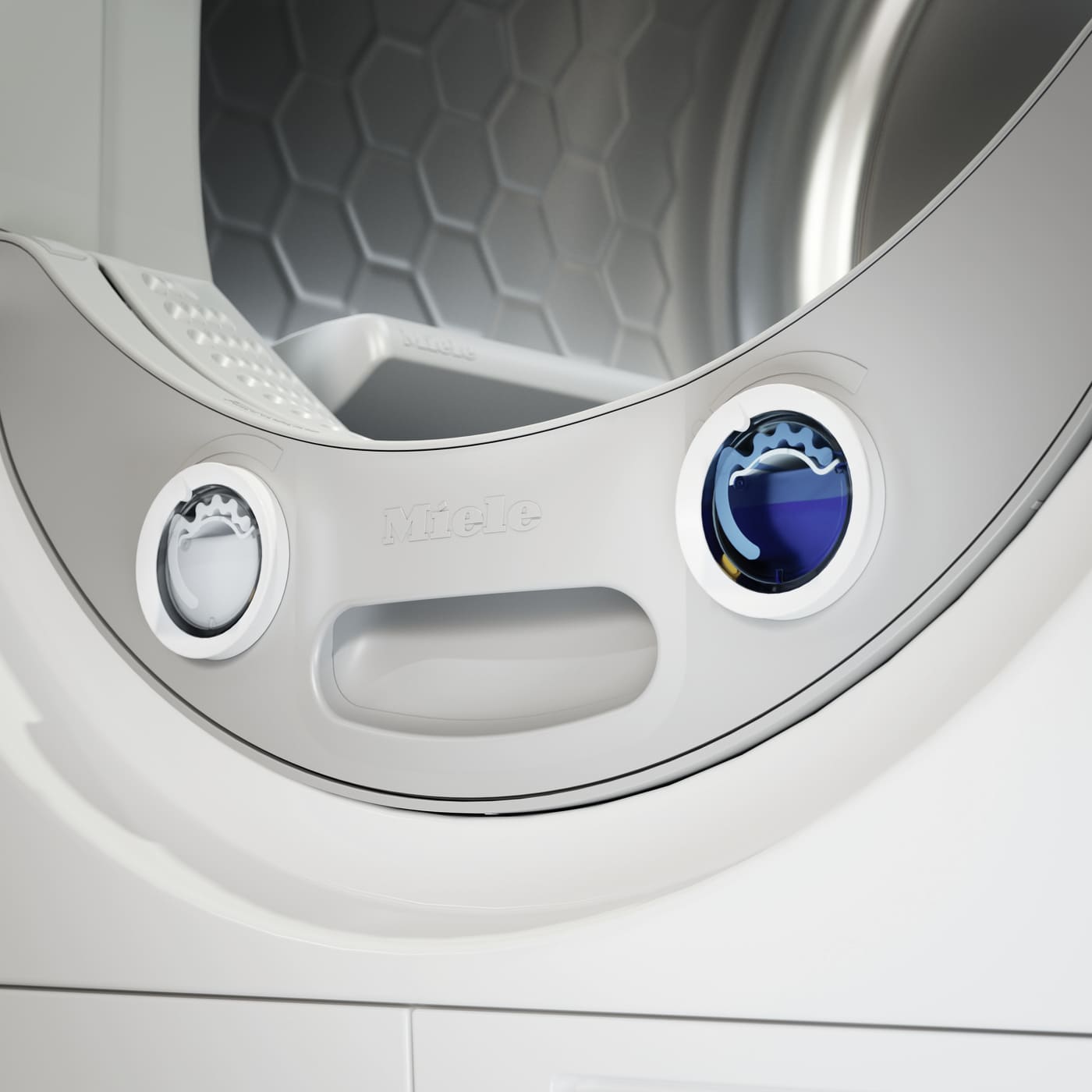Close-up of a white Miele front-loading washing machine door with two circular control dials and a hexagonal drum interior visible in the background.