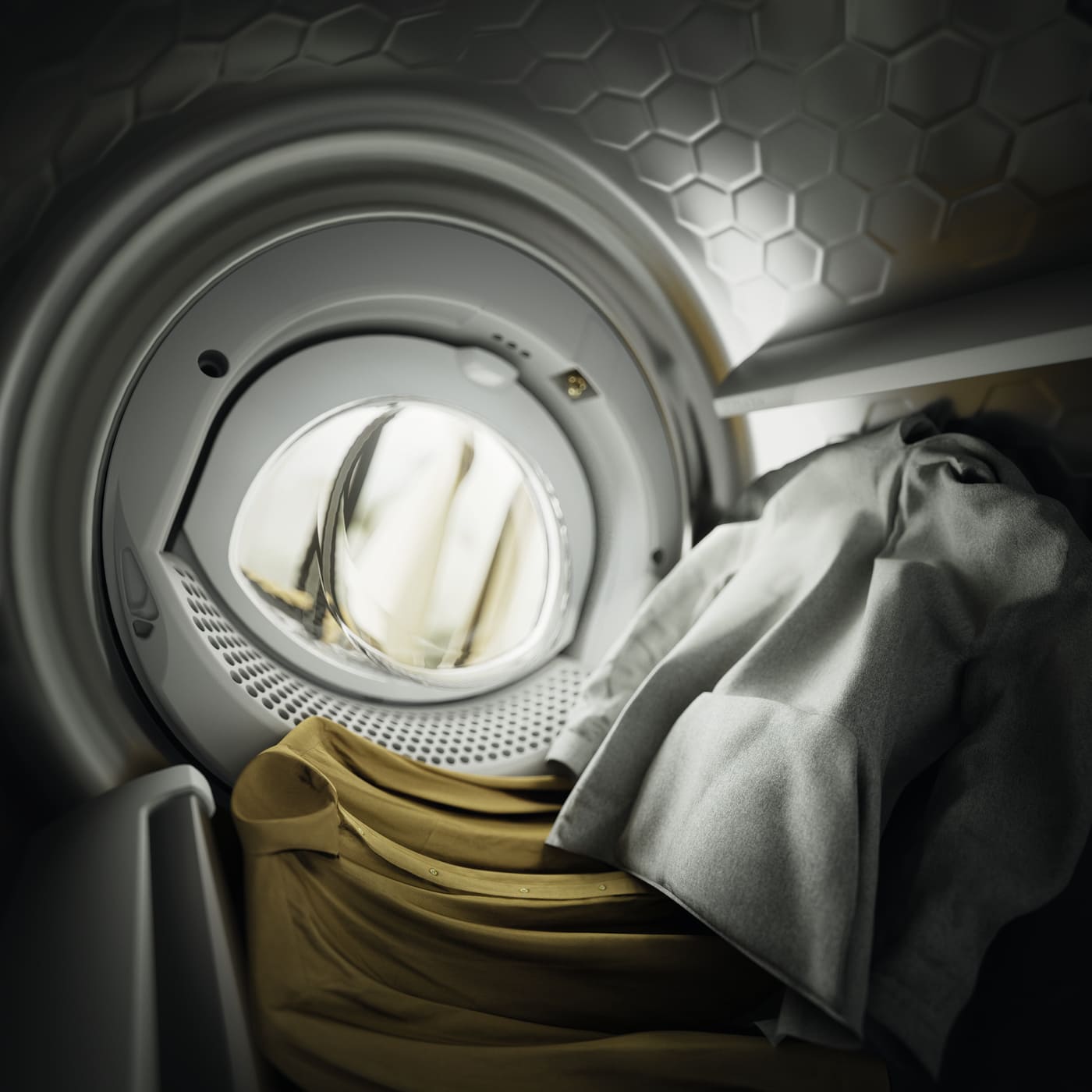 Front-loading washing machine drum with tan and gray laundry inside.