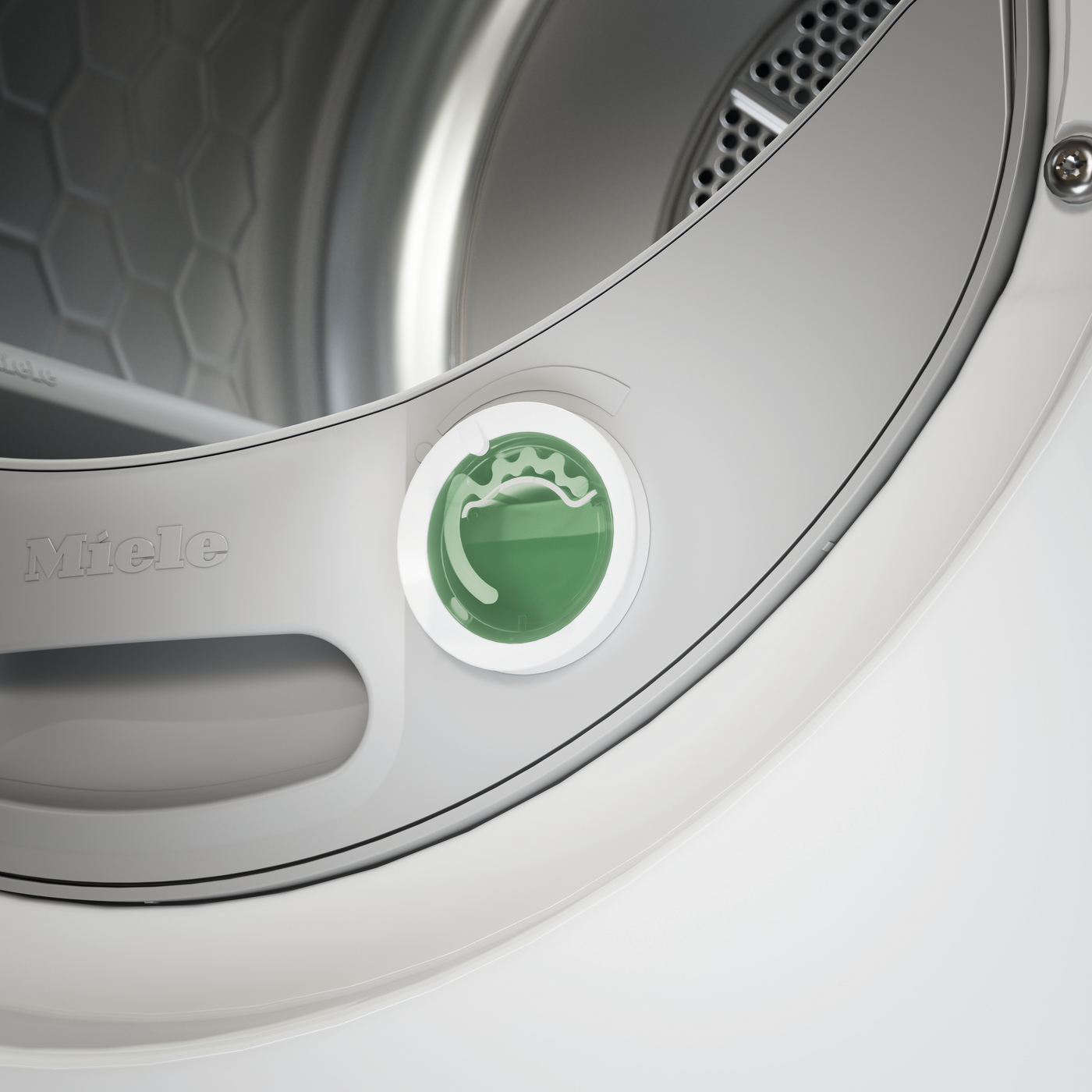 Close-up of a Miele front-loading washing machine drum with a green circular access cap inside the door opening