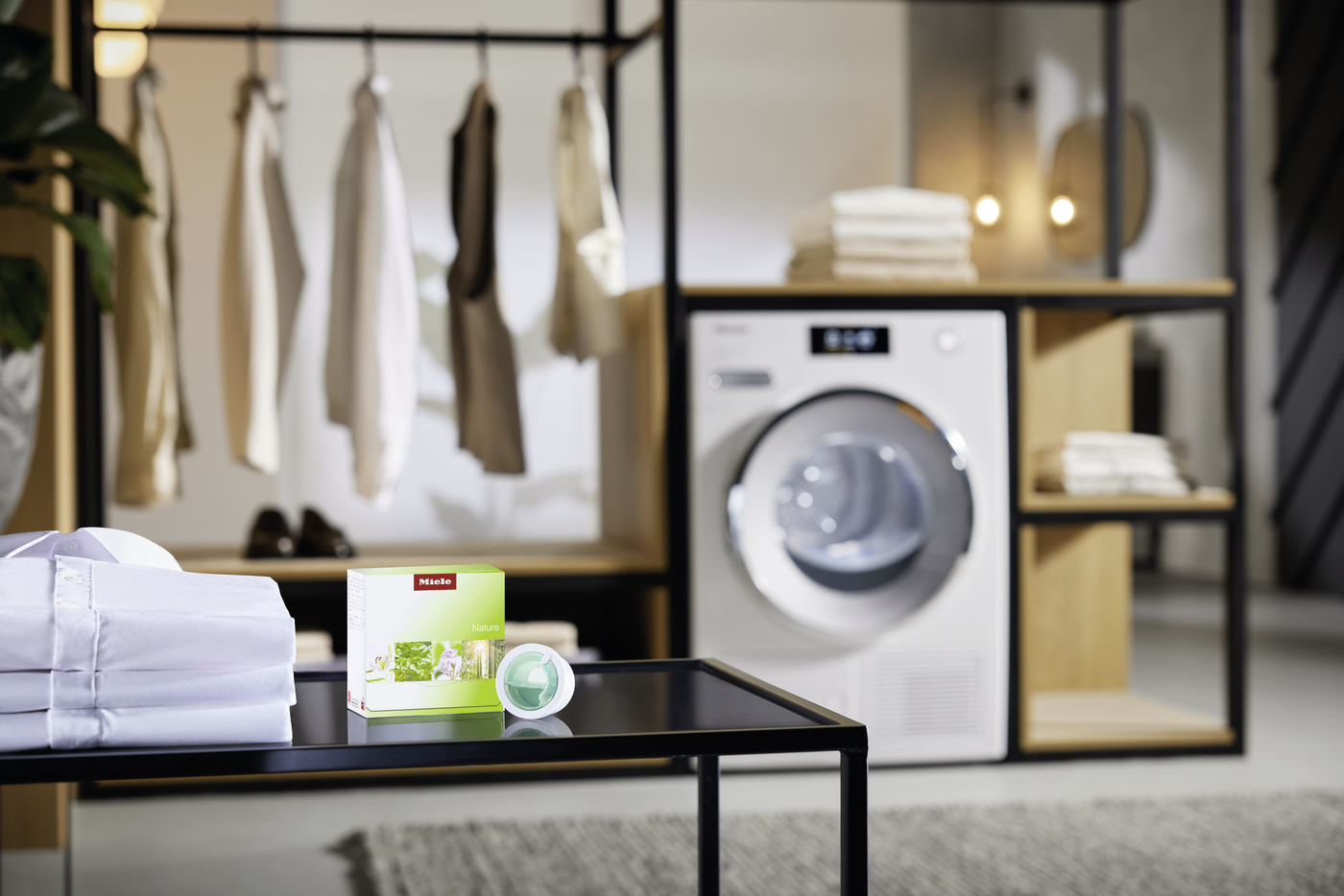 Modern laundry room display with a front-load washing machine, open shelves, and neatly folded towels in the background.