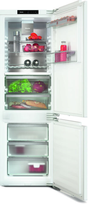 White, two-section refrigerator with top fridge and bottom freezer, open to reveal fruits, vegetables, beverages, and organized drawers.