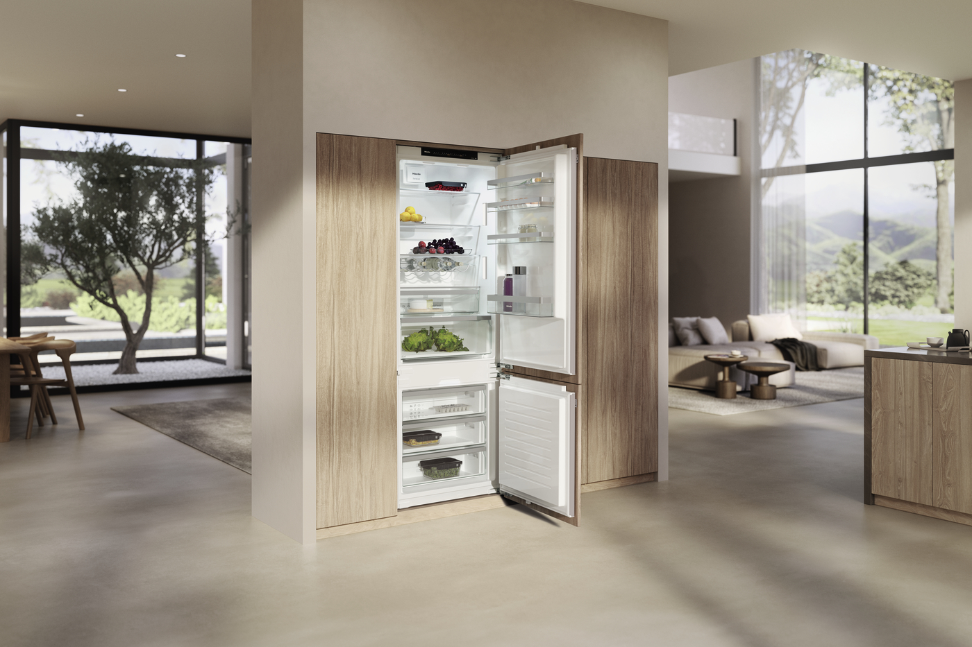 Built-in refrigerator with doors open in a modern, open-plan kitchen showing organized shelves and drawers inside.