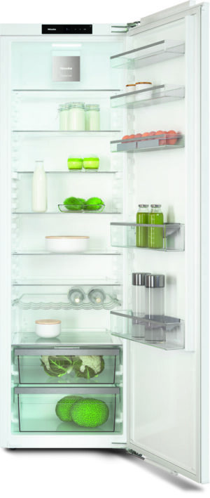 Open white refrigerator showing shelves with milk, jars, eggs on the door, and leafy greens in the lower drawers.