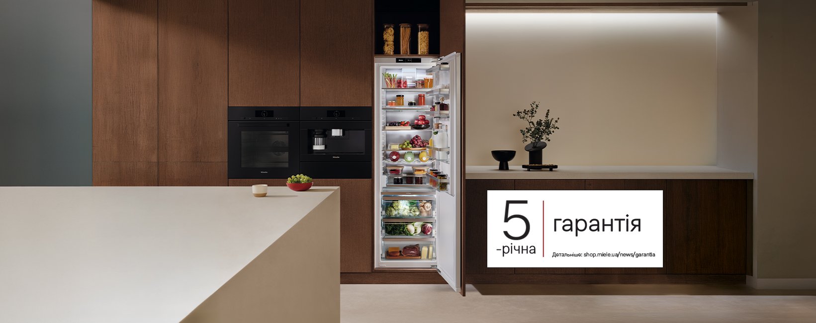 Open fridge in a modern wood-toned kitchen, displaying groceries; a 5-річна гарантія banner sits on the right.