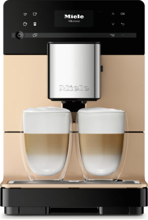 Rose-gold Miele coffee machine with two latte glasses under the spouts, foamed milk visible