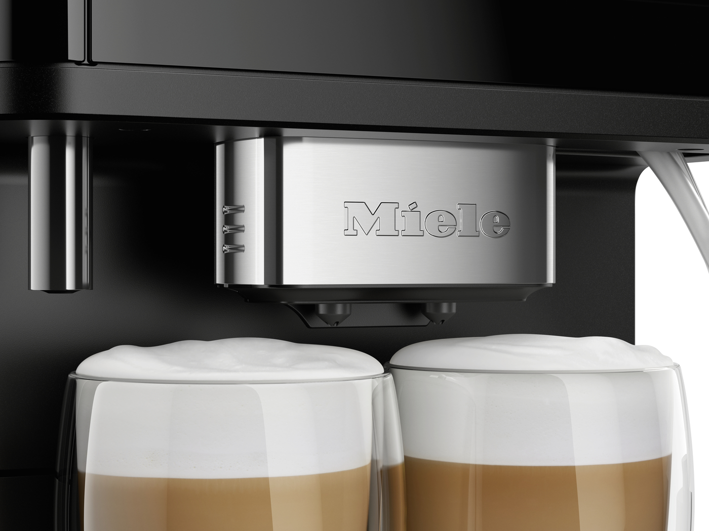Close-up of a Miele espresso machine dispensing into two glass cups filled with layered cappuccinos topped with foam.