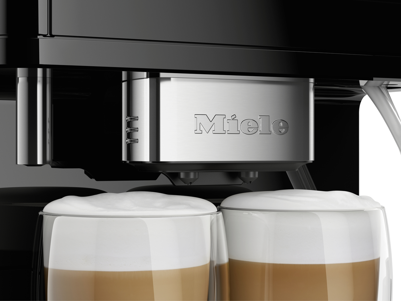Close-up of a Miele coffee machine dispensing two cappuccinos with thick milk foam in glass cups below the spouts.