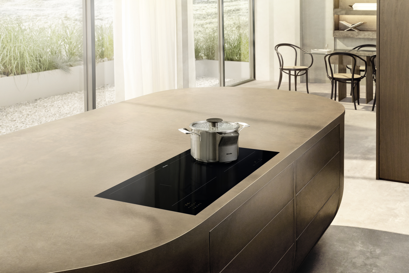 Modern kitchen island with a built-in black induction cooktop and a stainless steel pot on top.