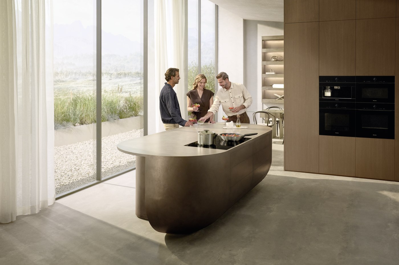 Three adults toast with drinks around a curved, bronze kitchen island in a bright, modern kitchen with large glass walls and outdoor view.